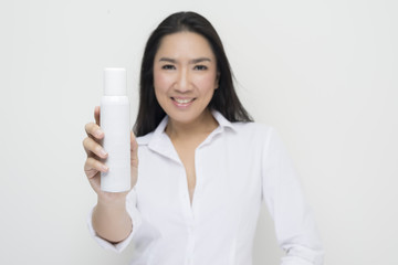 Beauty series: Asian woman holding white spray bottle against white background
