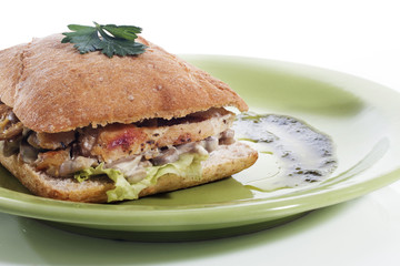 Healthy chicken and mushroom sandwich on green plate over white background