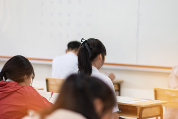 Blurred of Thai students writing on a paper for exams and admissions in high school, Thailand : education concept