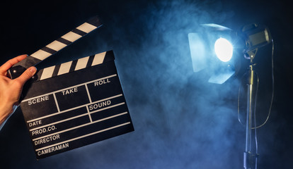 Operator holding clapperboard, studio light on background