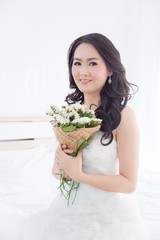 Beautiful asian bride holding flower boquet in room