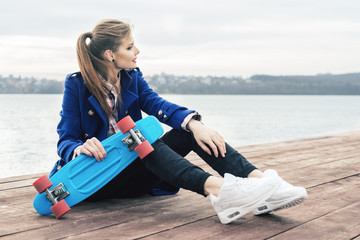 Fashion portrait of pretty young woman hipster with skateboard