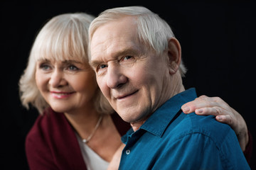 portrait of smiling senior man and woman on black