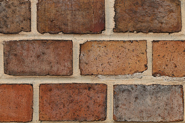 The wall of the old bright red brick with beige stitching.