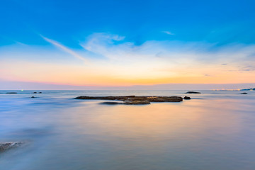 Long exposure shot of calmness sea and the rock in beautiful sunset sky