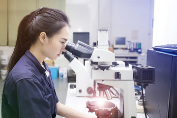 female scientist looking in microscope in laboratory