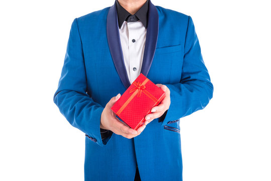 A man in suit holding red present box over white background