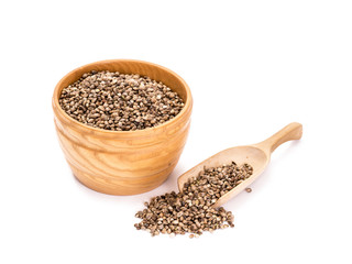 Wooden bowl with hemp seeds and a spoon to the right of it on white background