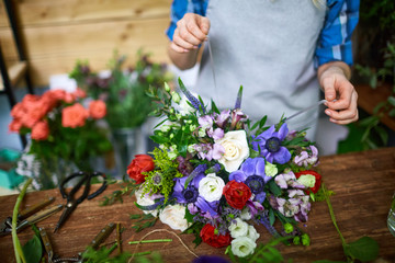 Fresh floral bouquet being tied by florist