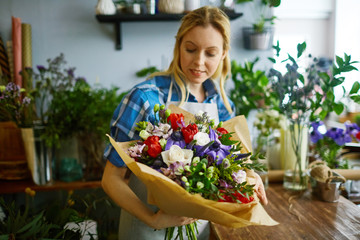 Young florist looking at arranged bouquet in her hands