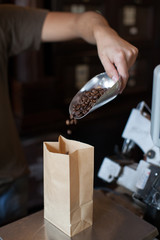 Seller man pour coffee beans in a paper bag, weighs and sells in the coffee shop - 139573174