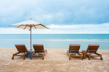 Beach chairs on the sand beach with cloudy blue sky