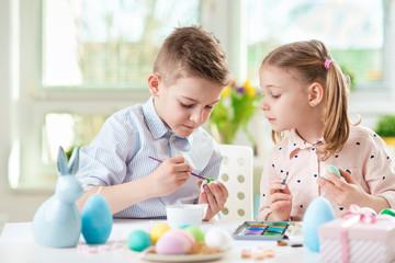 Two happy children having fun during painting eggs for Easter in spring time