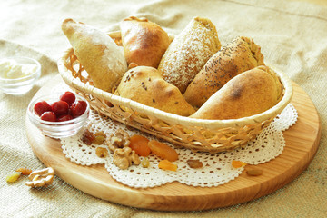 Russian pirozhki, baked patties or pies on basket with nuts and dried apricots
