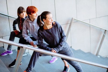 Group of three sports women stretching on the stairs before run.