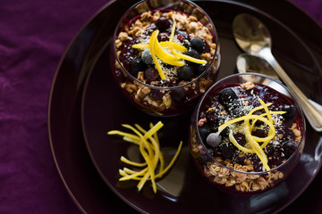 Healthy breakfast: blackberry and banana smoothie with granola on magenta plate. Selective focus