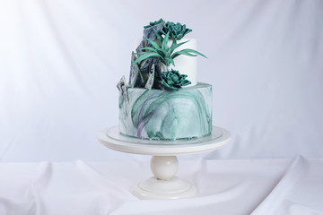 Wedding cake decorated like a stone marble with green flowers