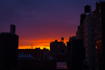 Fototapeta na wymiar Watching the sun setting on an Upper West Side rooftop, colorful sky, water towers