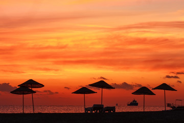 Silhouette parasol on coast on background of beautiful sunset