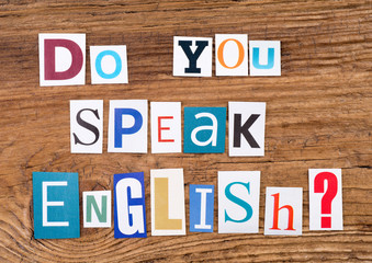 Question "Do you speak English?" in cut out magazine letters on wooden background 