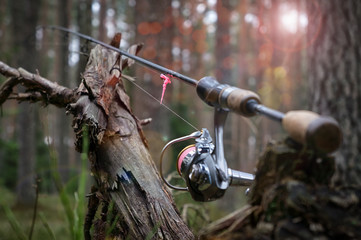 Spinning rod with a reel spring on the background of wood.