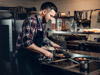 Cheef cook prepairing a meat on a kitchen.
