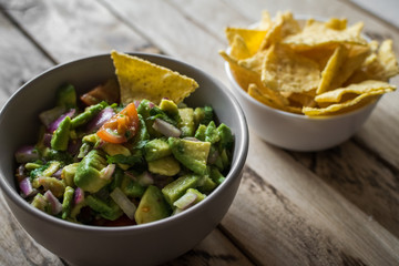Guacamole and tortilla. Rustic wooden background.