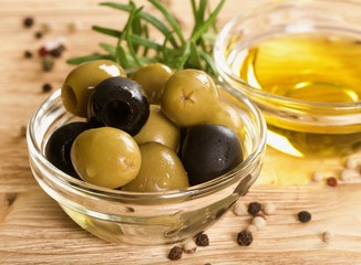 green and black olives with oil on a wooden background