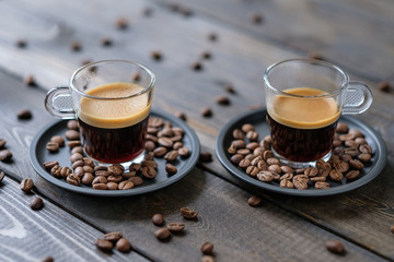 Two cups of espresso and coffee beans on a wooden table