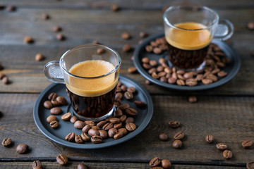 Two cups of espresso and coffee beans on a wooden table