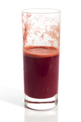 A glass of half full red healthy juice isolated over a white background