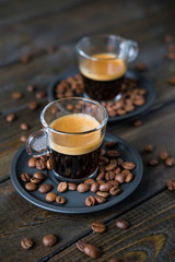 Two cups of espresso and coffee beans on a wooden table