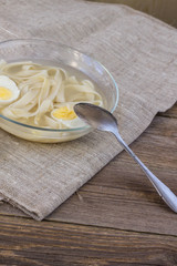 cup of chicken soup with noodles and eggs