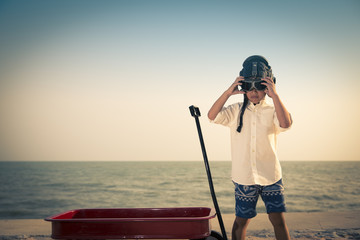 Obraz premium Boy playing aviator on beach, retro tone photo
