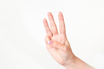 Close up of caucasian female caucasian hand isolated on white background. Young woman shows 3 fingers while counting. Horizontal color image.