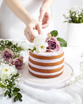 Spring Mood. Sponge Cake With Whipped Cream Decorated Flowers Roses And Freesia. Tender Wedding Cake In White With Pastel Colors. Delikate Female Hands In The Frame A Big Cake.