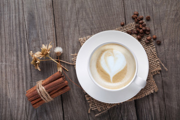 cup of cappuccino coffee on old vintage wooden table, dry flower , cinnamon, top view
