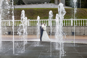 Groom and bride next to a fountain and high water jets