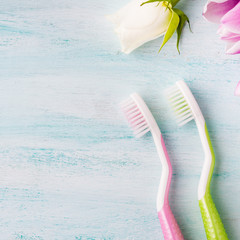 Two pastel toothbrushes with flowers herbs over green textured background. Spring colors. Personal dental health care. Healthy couple concept