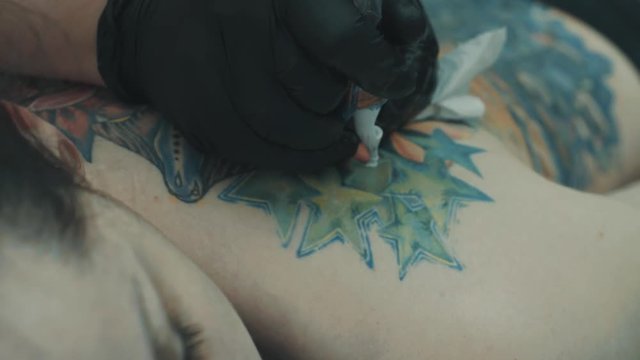 Tattooist making a tattoo on the girl's back