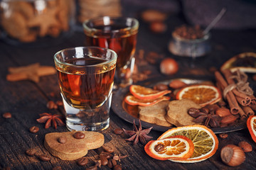 Whiskey or liqueur, cookies, spices and decorations on wooden background.