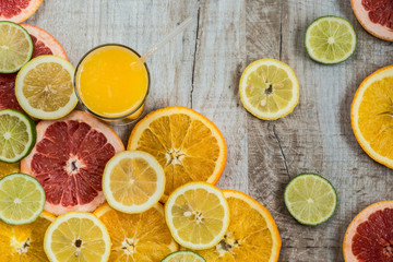 Fototapeta na wymiar glass of orange juice on the wood background with slices of citrus