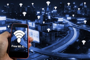 smartphone on hand with free wifi icon on night city background, technology and communication concept, color tone effect