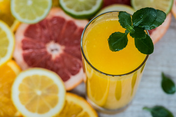 glass of orange juice on the wood background with slices of citrus