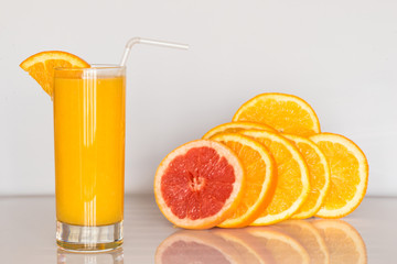 glass of orange juice on the white background with slices of citrus