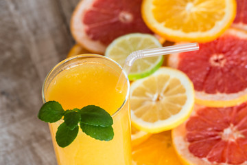 glass of orange juice on the wood background with slices of citrus