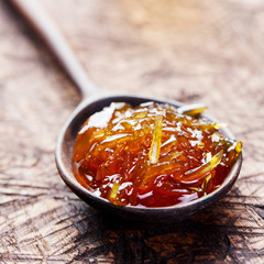 Orange, grapefruit confiture, jam in a wooden spoon. Close up.