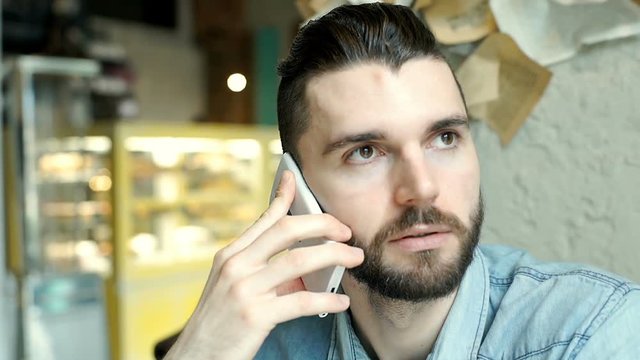 Handsome man receives bad news while speaking with someone on cellphone
