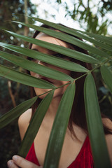 Vertical image of woman hiding behind the plant
