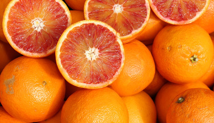 Ripe oranges and an orange cut in the stall of greengrocer